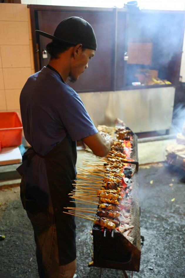 A worker preparing satay on the grill.