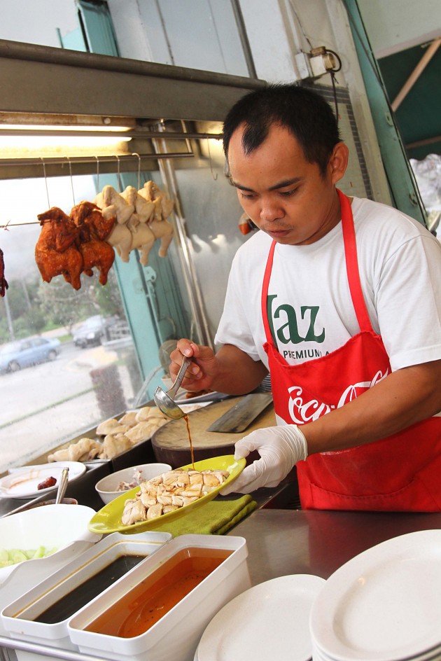 A worker preparing the steamed chicken to be served to customers at Satellite Chicken Rice Restaurant.