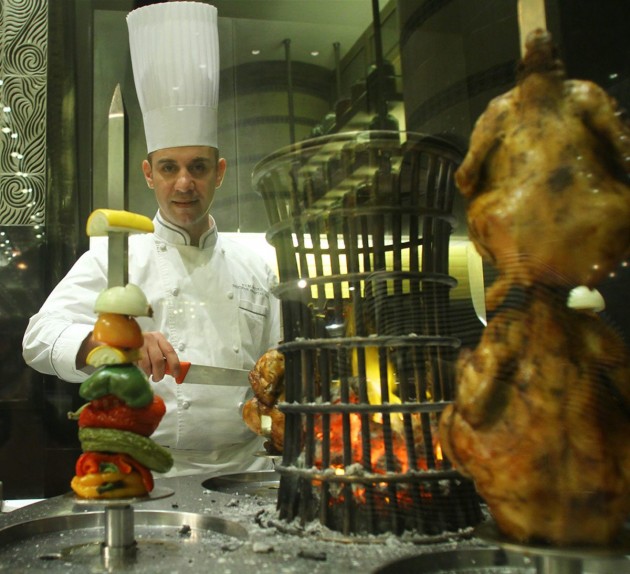 Chef Ali slicing chicken pieces at the grill section.