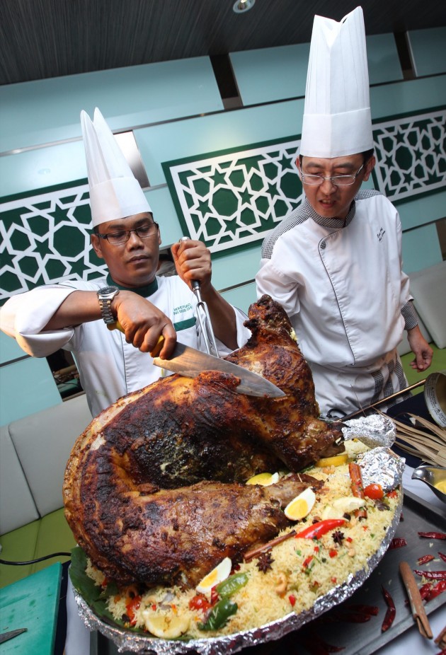 Eastin Hotel Petaling Jaya sous chef Muhammad Fuad Abdullah carving the Kambing Panggang Rempah Kuzi bersama Nasi Arab. With him is Leong.