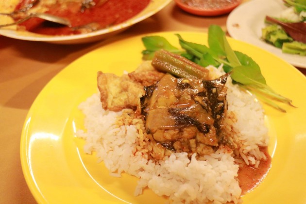 Catfish in gravy served on a plate of hot rice.