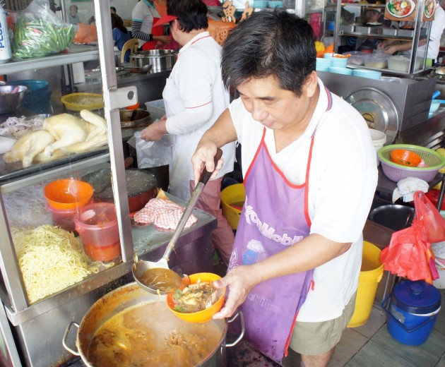 Penang Laksa stall owner Ooi preparing orders for customers.