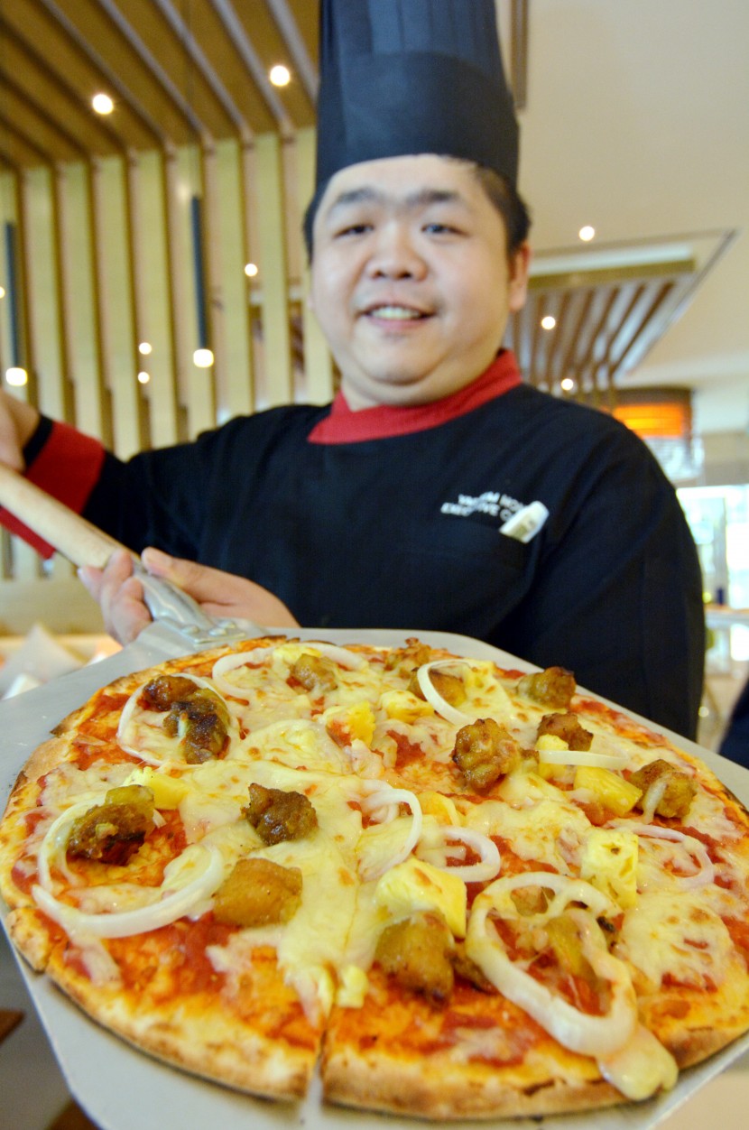 Chef Yap Kim Hon, who has 20 years of experience under his belt, with one of his signature fusion dishes, the Oriental Hawaiian Pizza. 