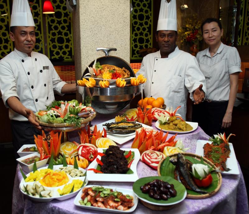 Ritz Garden Hotel Ipoh manager Lily Chee (right) along with chefs Mohd Suhaimi Salleh (left) and Ahmad Hydress with the Ramadan buffet spread of Malay styled kampung foods.