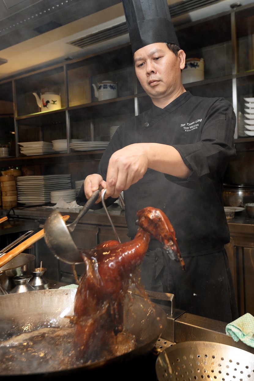 Tan preparing the Crispy Roasted Duck, a popular dish at the restaurant.