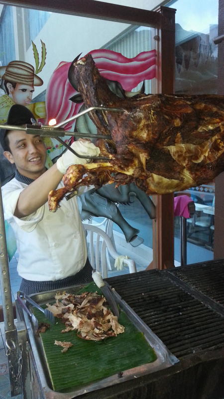 A chef serving whole roasted lamb to diners.