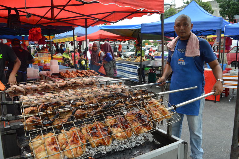 Faqrul Ismadi Oman turning the chickens over a charcoal fire at the Ramadan Bazaar.
